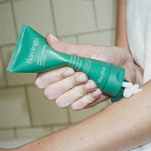 Woman squeezing lotion onto her arm from a green tube of Flamingo Mini Daily Moisturizing Lotion